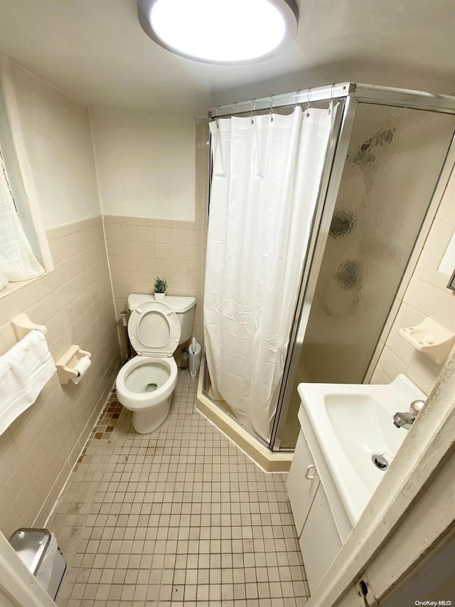 bathroom with tile patterned floors, walk in shower, sink, tile walls, and toilet