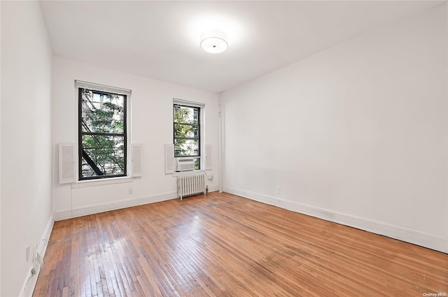 spare room featuring hardwood / wood-style floors, cooling unit, and radiator heating unit