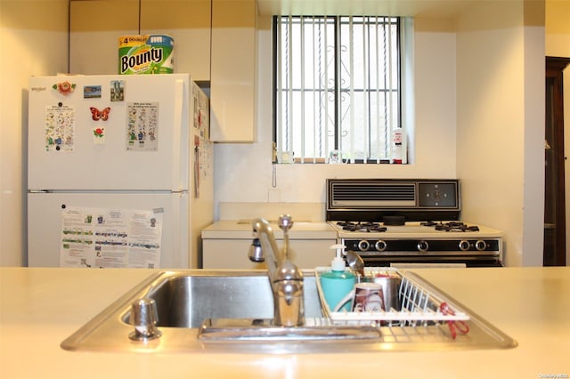 kitchen with white refrigerator, black range with gas stovetop, and white cabinetry