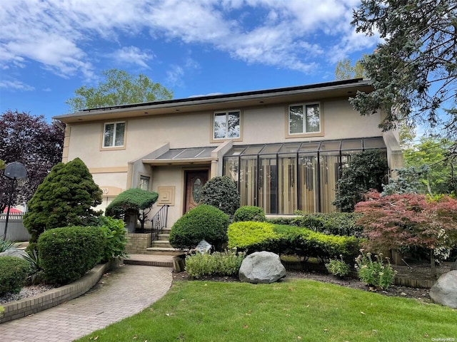 view of front of home with a sunroom and a front lawn