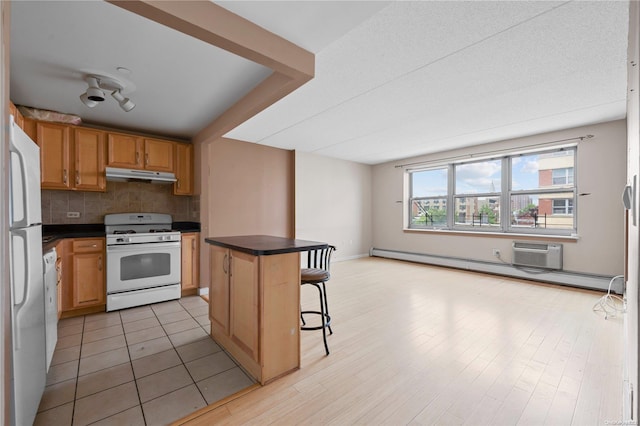 kitchen with a center island, white appliances, backsplash, a baseboard heating unit, and a breakfast bar area