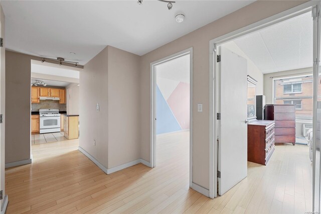 hallway featuring light hardwood / wood-style floors, rail lighting, and a baseboard radiator