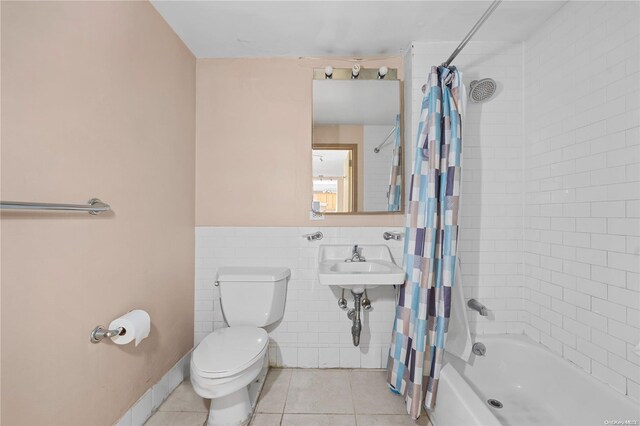 full bathroom featuring sink, shower / bathtub combination with curtain, tile walls, tile patterned flooring, and toilet