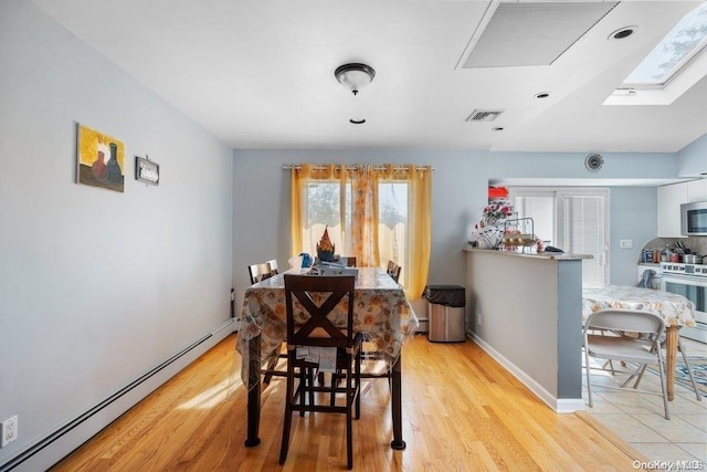 dining area featuring a skylight, light hardwood / wood-style flooring, and a baseboard heating unit