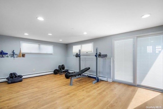 exercise area featuring a baseboard heating unit and light hardwood / wood-style flooring