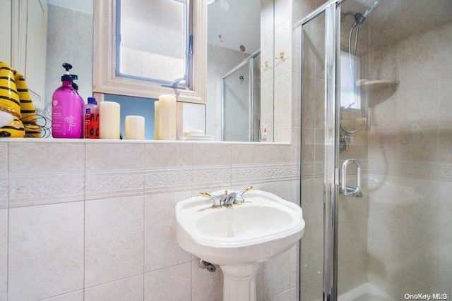 bathroom with a shower with door and tile walls