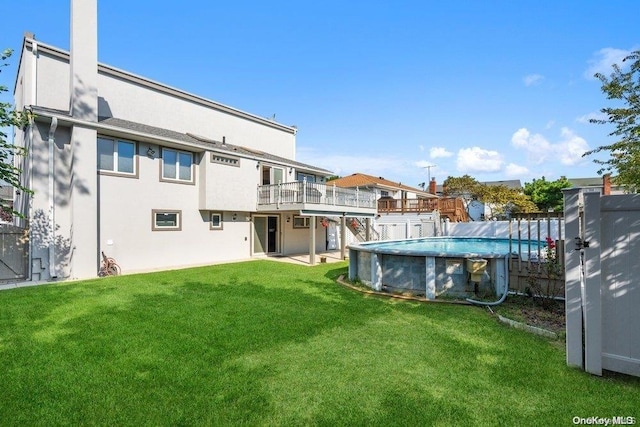 rear view of house featuring a pool side deck and a lawn