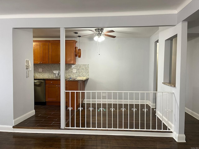 kitchen with stainless steel dishwasher, dark hardwood / wood-style flooring, light stone countertops, and backsplash