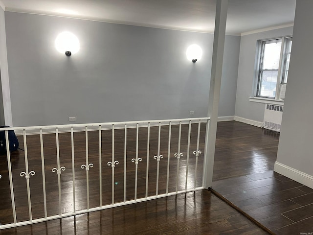 empty room featuring radiator heating unit, dark hardwood / wood-style floors, and ornamental molding