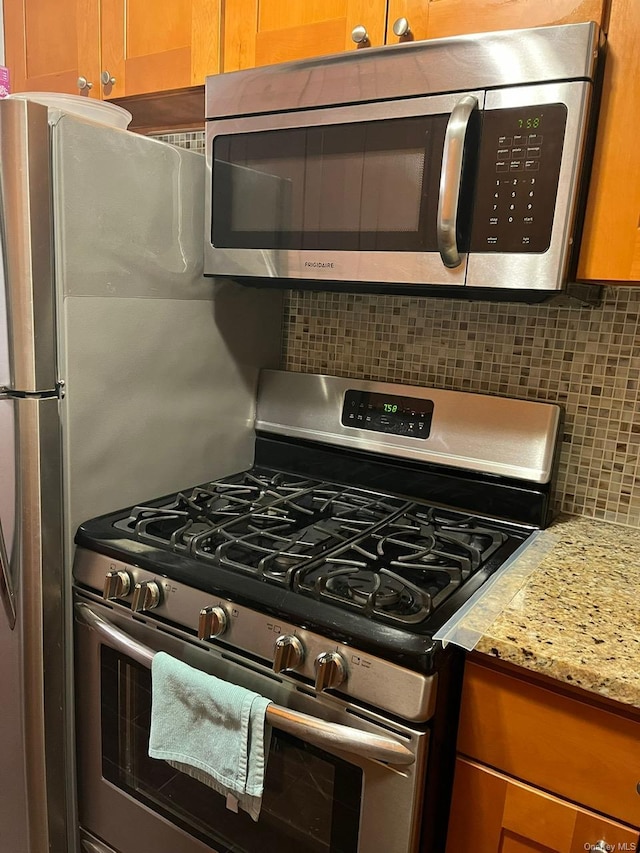 kitchen featuring decorative backsplash, light stone counters, and appliances with stainless steel finishes