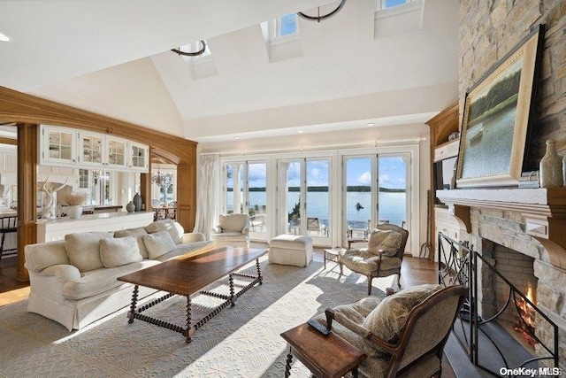 living room with a fireplace, hardwood / wood-style floors, a water view, and high vaulted ceiling