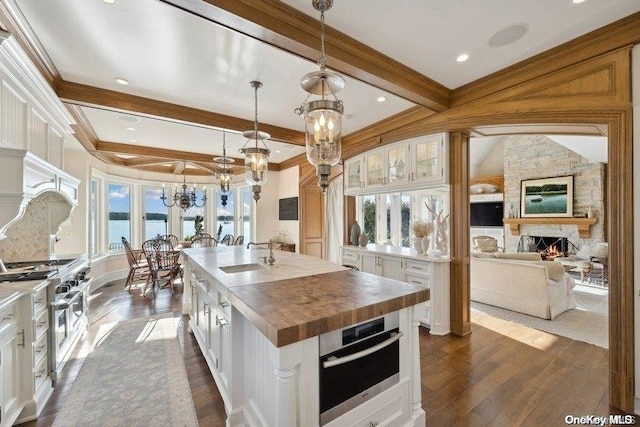 kitchen featuring white cabinets, appliances with stainless steel finishes, a kitchen island with sink, and hanging light fixtures