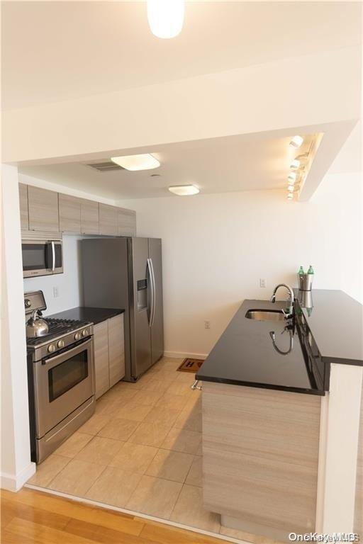 91-16 Shore Front Pkwy Unit 6I, Seaside, NY 11693 - kitchen with appliances with stainless steel finishes, a sink, dark countertops, baseboards, and modern cabinets