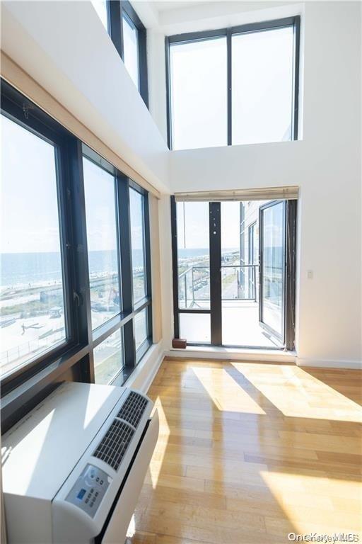 91-16 Shore Front Pkwy Unit 6I, Seaside, NY 11693 - spare room featuring light wood-style floors, baseboards, a high ceiling, and a water view