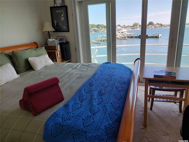 carpeted bedroom with access to outside and a water view