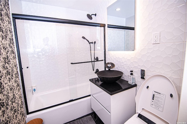 bathroom featuring vanity, combined bath / shower with glass door, and tile walls