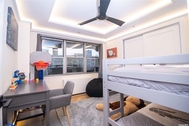 bedroom featuring ceiling fan, a raised ceiling, and wood-type flooring