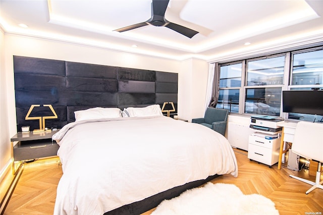 bedroom with a raised ceiling, ceiling fan, and light parquet flooring