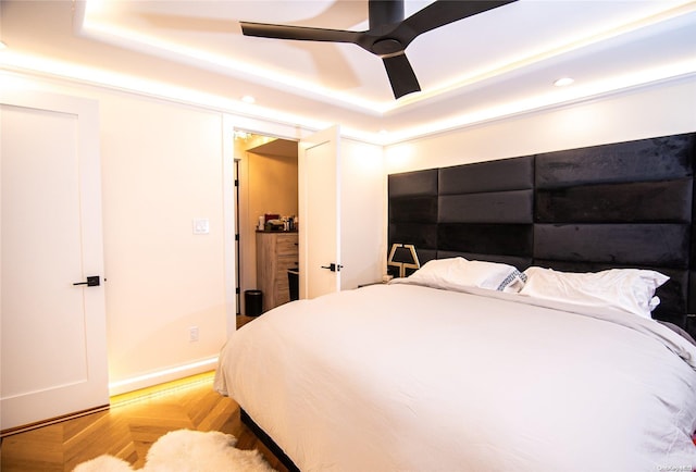 bedroom with parquet floors, a tray ceiling, and ceiling fan