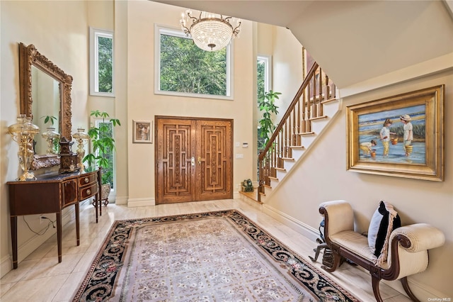 tiled foyer with high vaulted ceiling and an inviting chandelier