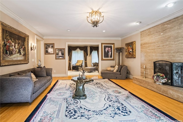 living room with a notable chandelier, wood-type flooring, ornamental molding, and a high end fireplace