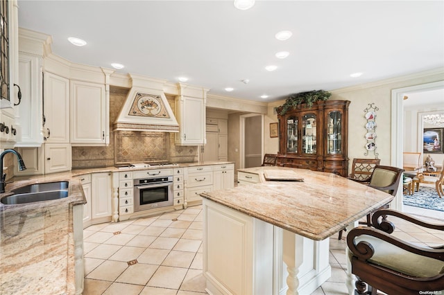 kitchen featuring a breakfast bar area, light stone counters, sink, and appliances with stainless steel finishes