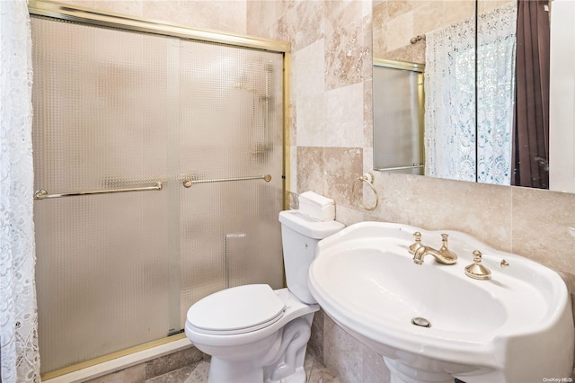 bathroom featuring sink, an enclosed shower, tile walls, and toilet