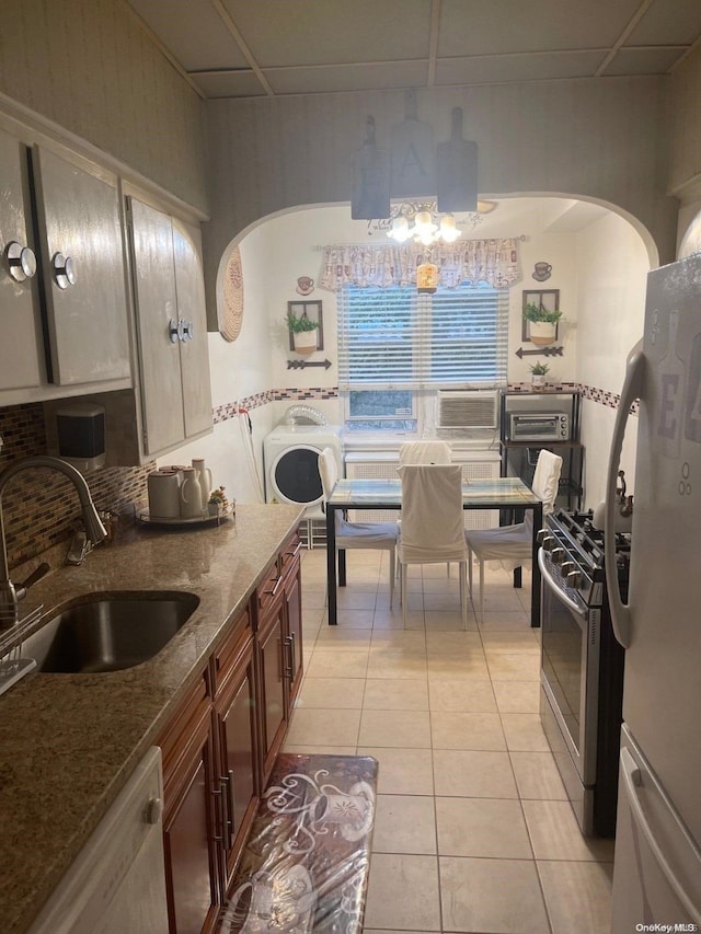 kitchen with stone counters, sink, a drop ceiling, white appliances, and light tile patterned flooring