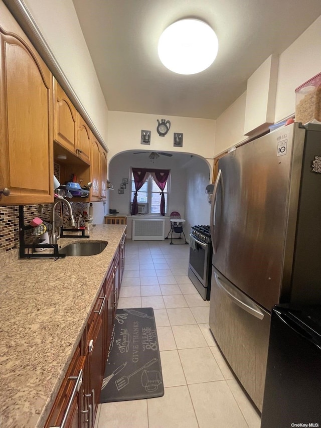 kitchen featuring appliances with stainless steel finishes, tasteful backsplash, light stone counters, sink, and light tile patterned floors