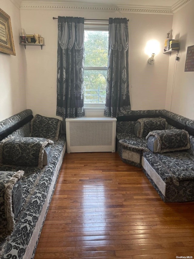 living area with radiator, crown molding, and dark hardwood / wood-style floors