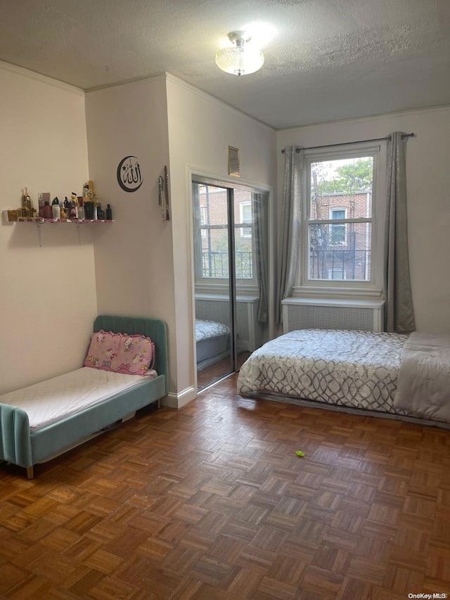 bedroom with a textured ceiling, dark parquet floors, and multiple windows