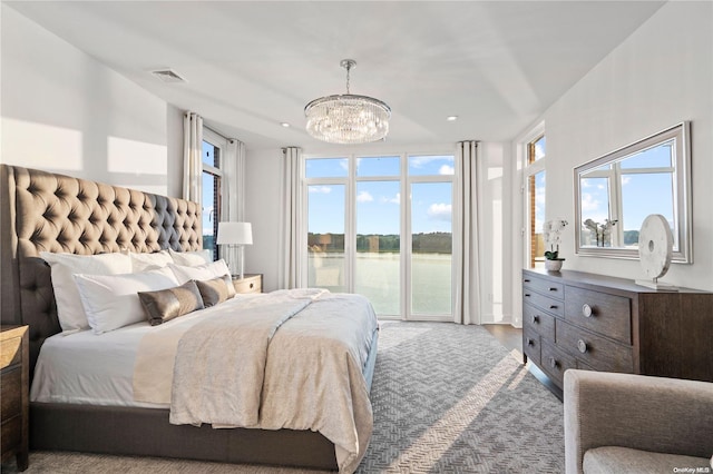 bedroom with a water view, wood-type flooring, access to exterior, and an inviting chandelier