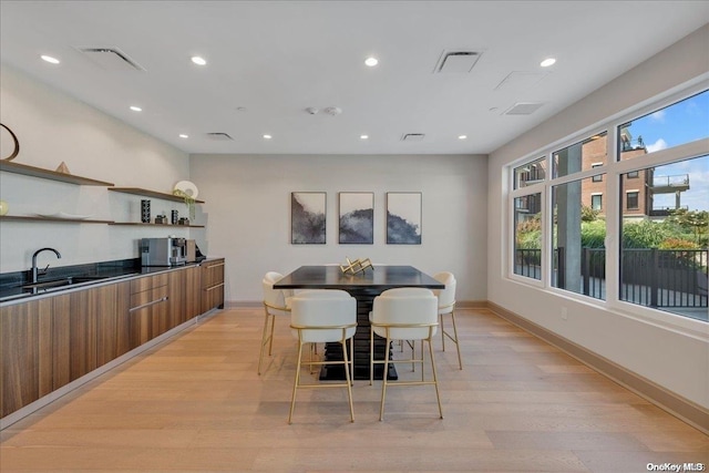 dining room with sink, a wealth of natural light, and light hardwood / wood-style flooring