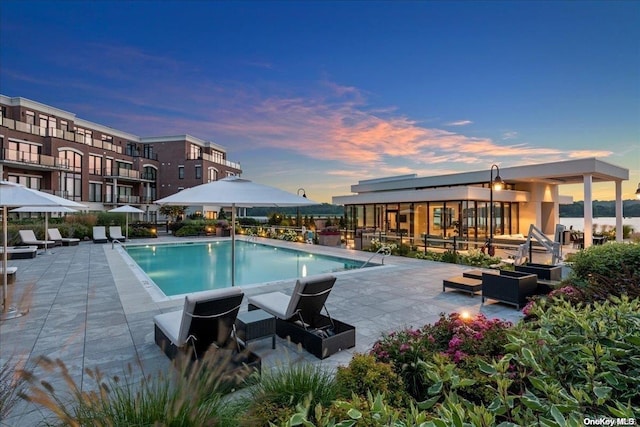 pool at dusk featuring a patio area