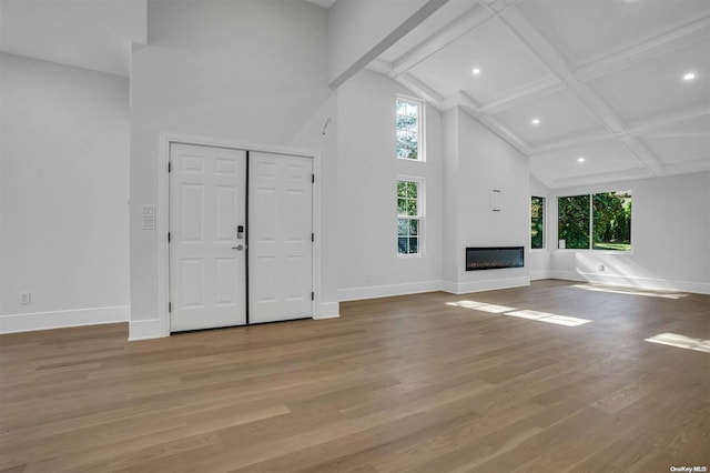 unfurnished living room with beamed ceiling, light hardwood / wood-style floors, high vaulted ceiling, and coffered ceiling