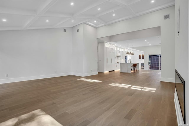 unfurnished living room featuring beamed ceiling, hardwood / wood-style floors, and coffered ceiling