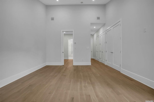 unfurnished living room featuring light hardwood / wood-style flooring and a high ceiling