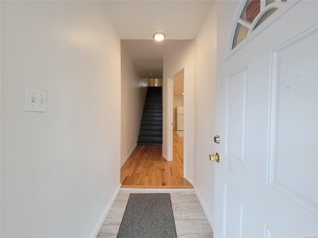 hall with stairway, baseboards, and light wood finished floors