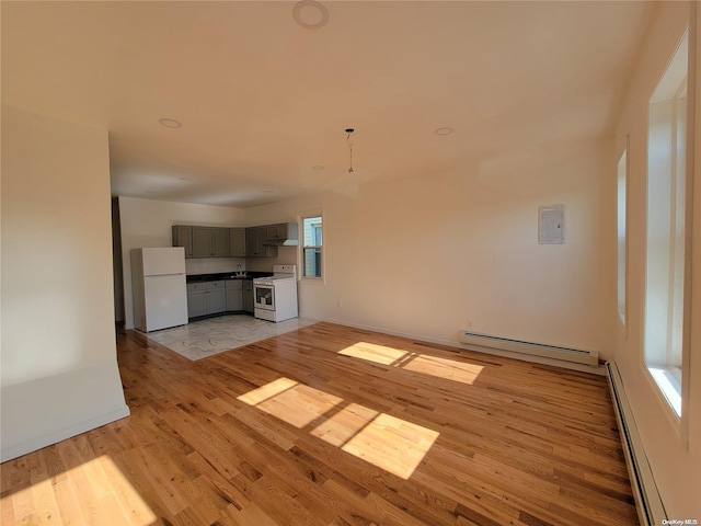 unfurnished living room with light wood-type flooring and a baseboard heating unit