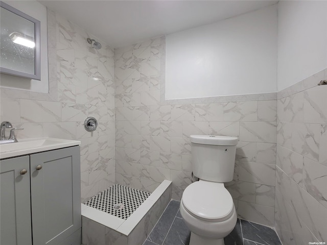 full bathroom featuring tile walls, tiled shower, toilet, and vanity