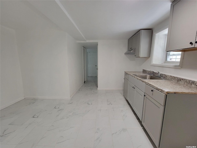 kitchen featuring gray cabinetry, baseboards, light countertops, marble finish floor, and a sink