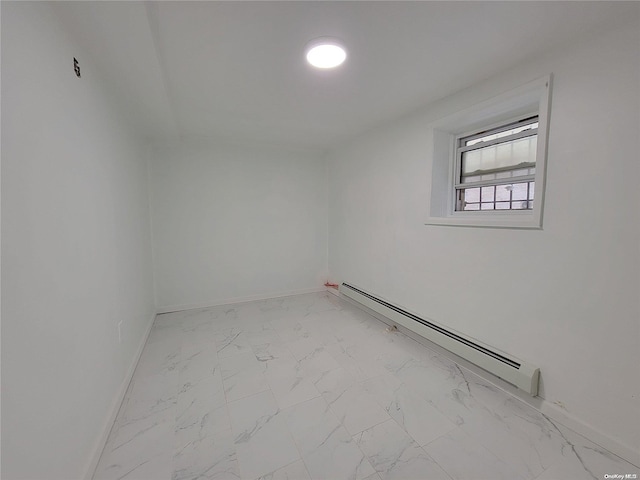 spare room featuring marble finish floor, a baseboard heating unit, and baseboards