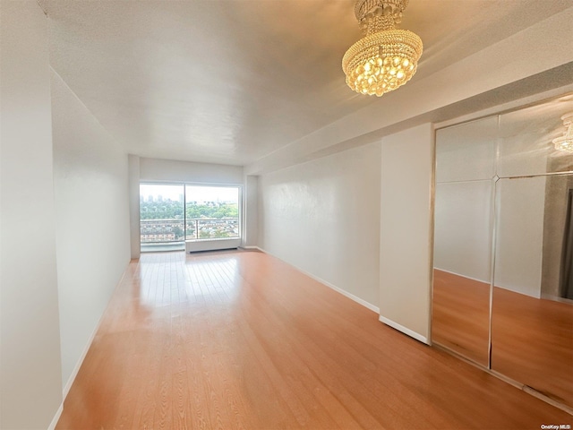 unfurnished room with an inviting chandelier and hardwood / wood-style flooring