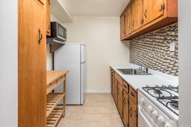 kitchen featuring decorative backsplash, white appliances, and sink