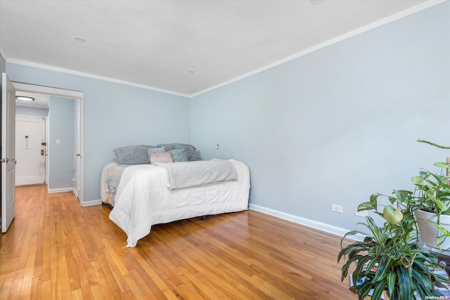 bedroom featuring light wood-type flooring and crown molding