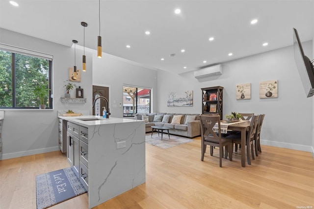 kitchen with kitchen peninsula, a wealth of natural light, hanging light fixtures, and light wood-type flooring