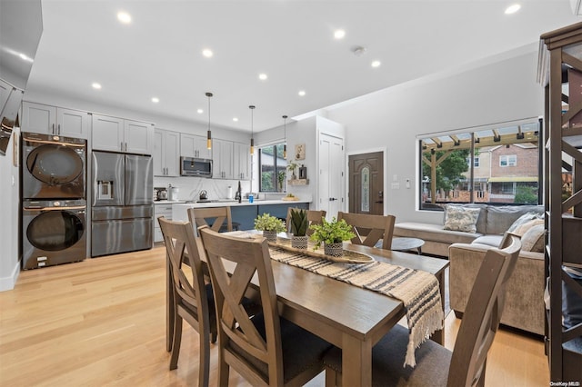 dining space with light hardwood / wood-style floors and stacked washer and clothes dryer