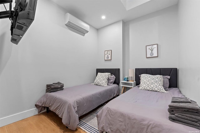 bedroom with light wood-type flooring and a wall mounted AC