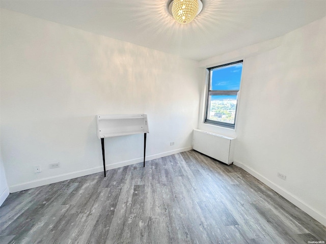 unfurnished room with hardwood / wood-style flooring and an inviting chandelier