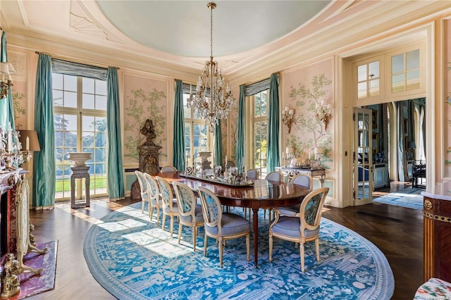 dining area with a tray ceiling, a chandelier, ornamental molding, and parquet flooring